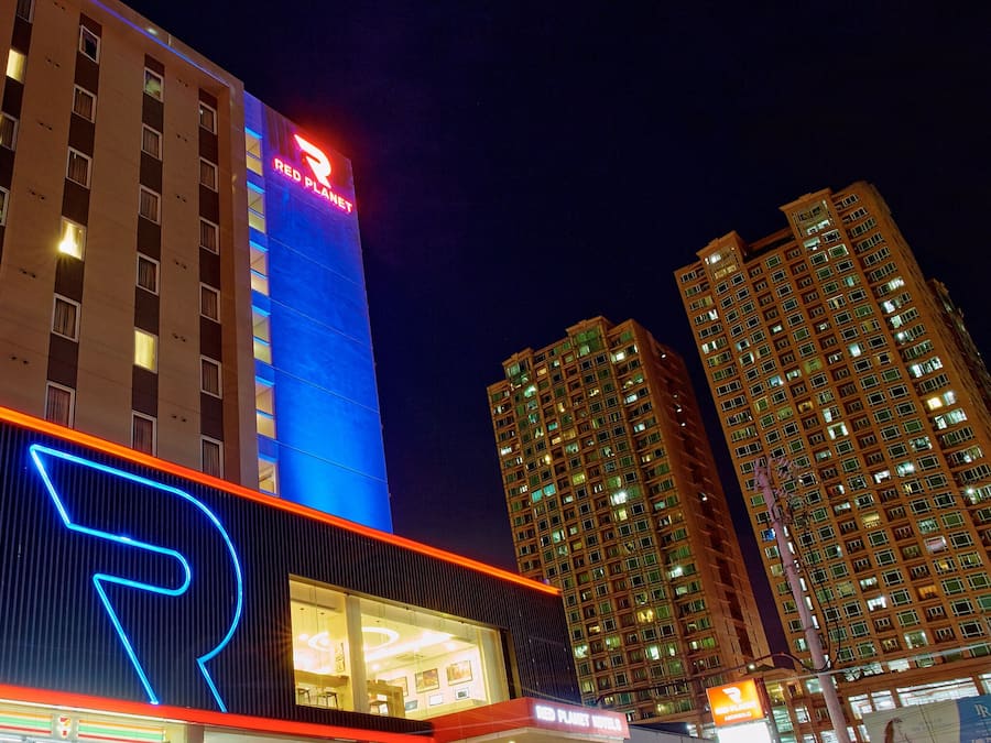 A modern hotel with a prominent 'R' logo, multiple floors, and illuminated signage.