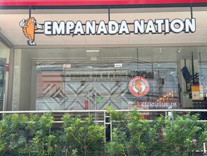 The storefront of Empanada Nation with a large sign and a mascot. - Red Planet Makati Amorsolo (Makati)
