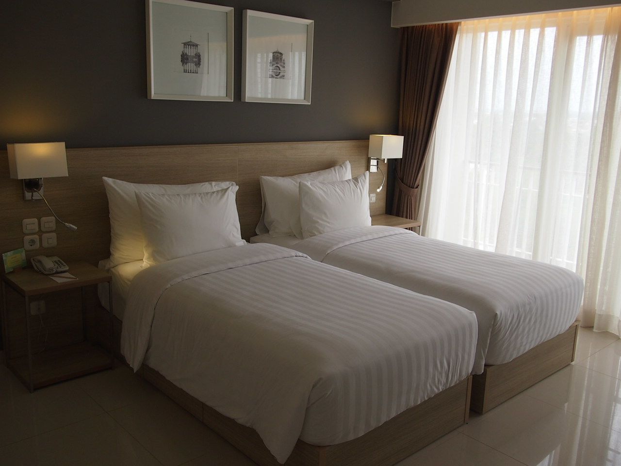 A double bed with a wooden headboard, two bedside tables with lamps, and framed artwork on the wall.