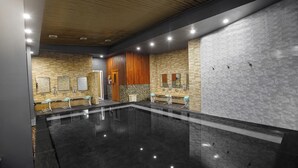 A modern bathroom with a large mirror, wooden paneling, and a black marble floor. - TreePark Karawang (Karawang)