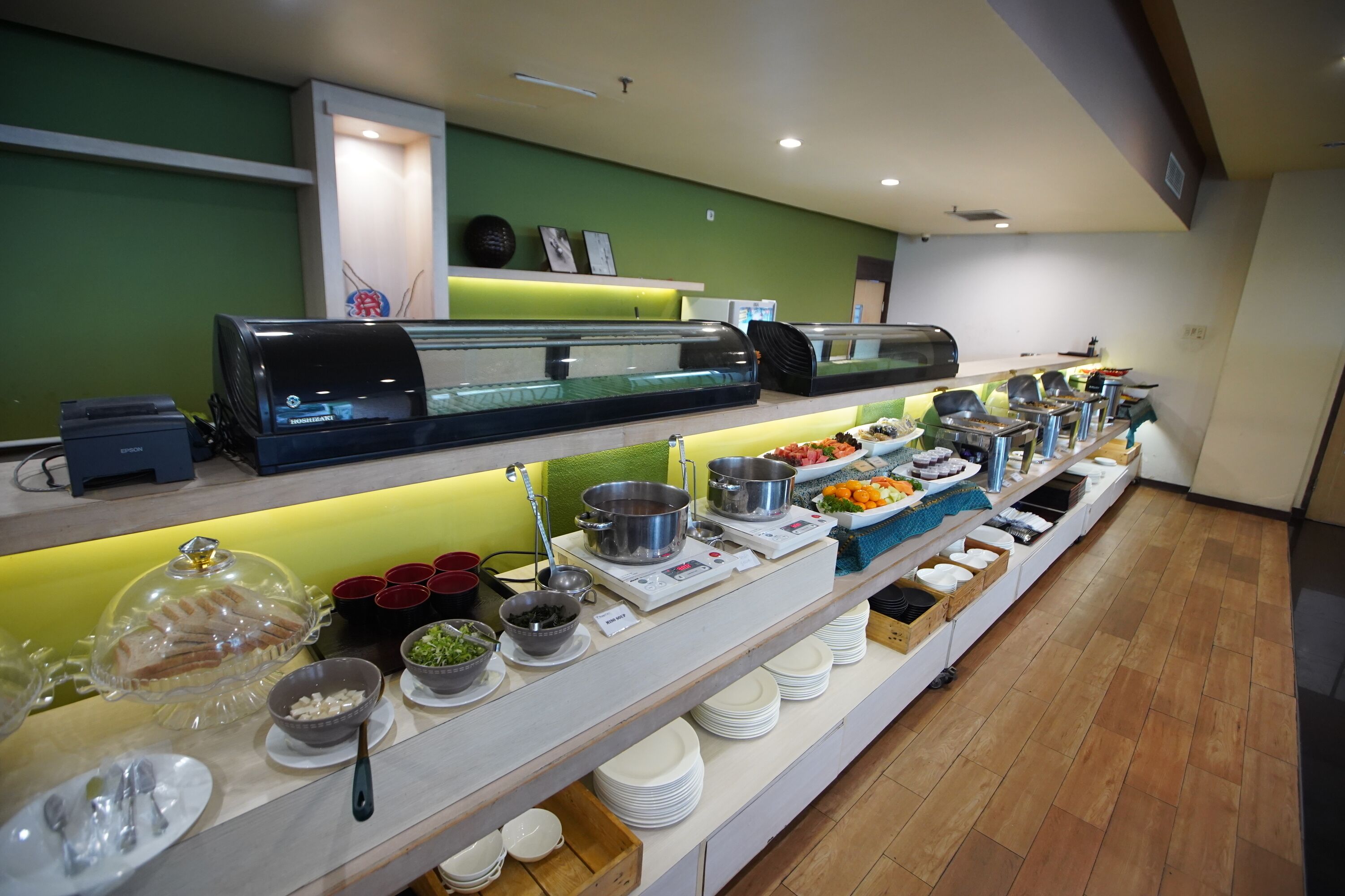 Een buffetopstelling met verschillende food stations, waaronder een saladebar en warme gerechten, in een moderne hotelsetting.