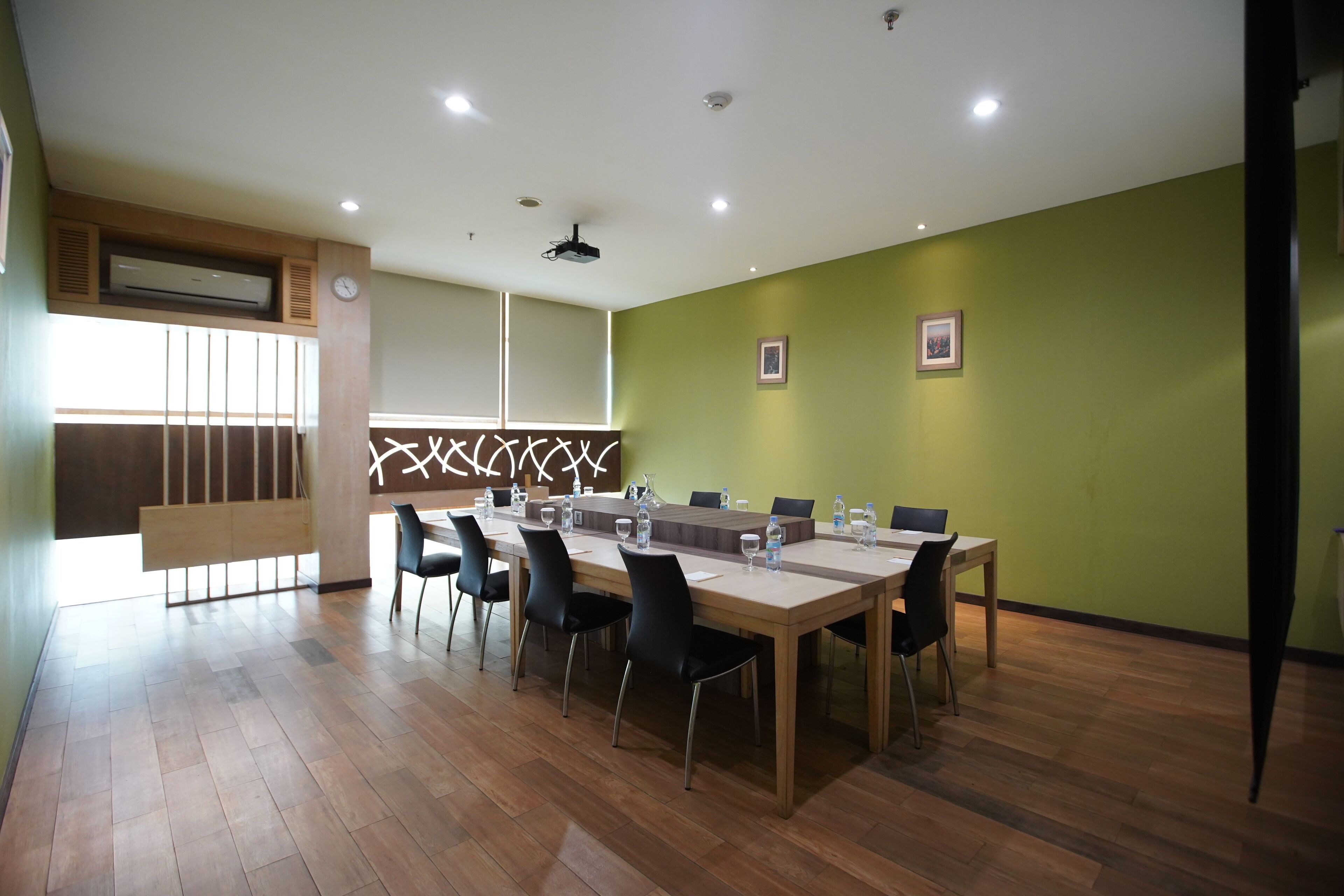 Une salle de conférence avec une longue table, des chaises et une horloge au mur.