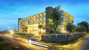 A multi-story hotel with a modern design, featuring balconies on each floor and a well-lit entrance. - TreePark Karawang (Karawang)