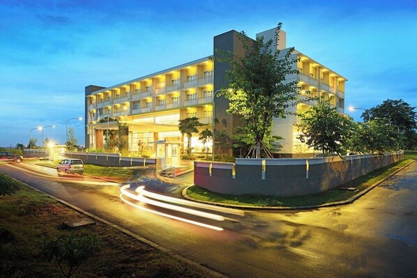 A multi-story hotel with a modern design, featuring balconies on each floor and a well-lit entrance. - TreePark Karawang (Karawang)