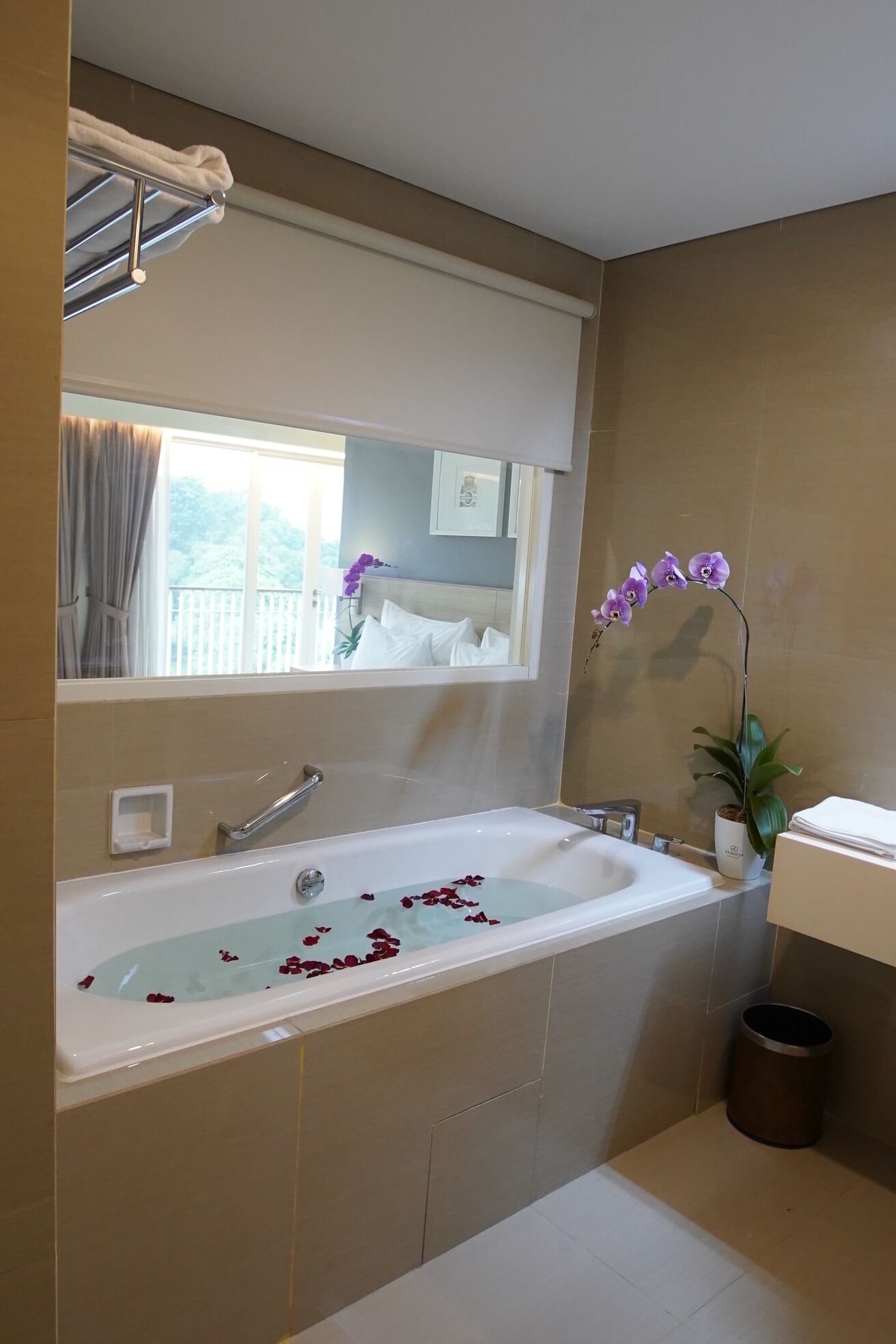 A bathroom with a bathtub, a sink, a mirror, and a potted orchid.