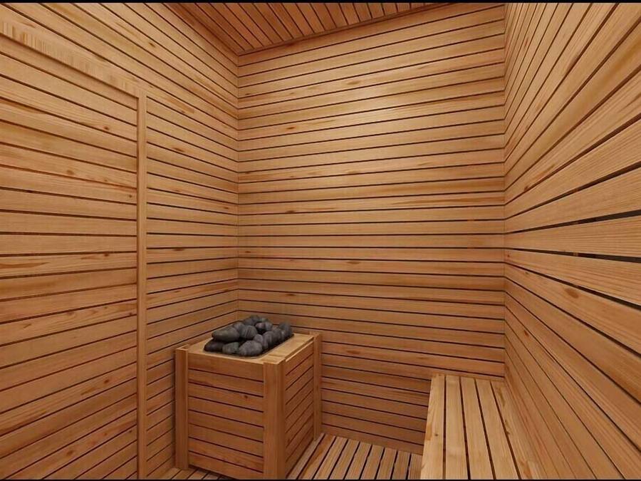 Una sauna de madera con paredes de listones y un banco con piedras calientes.