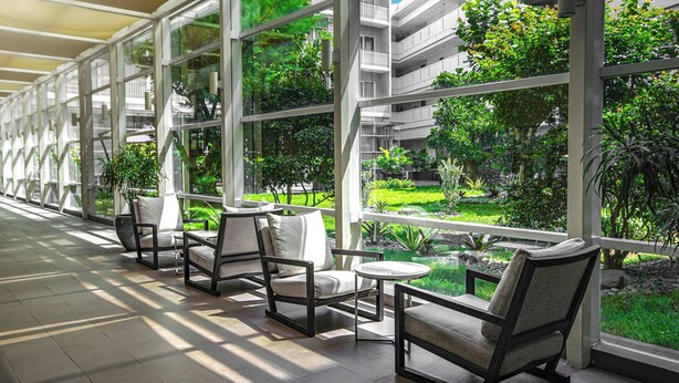 A modern indoor garden with seating areas and large windows overlooking a lush green landscape. - TreePark Karawang (Karawang)