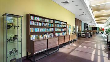 A spacious library with multiple bookshelves and a glass display case with model bicycles.
