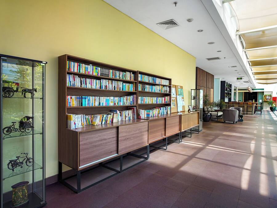 A spacious library with multiple bookshelves and a glass display case with model bicycles.
