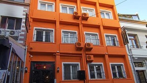 Um edifício de vários andares com fachada laranja vibrante, grandes janelas emolduradas por branco e aparelhos de ar condicionado.