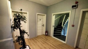 Um corredor com piso de madeira, um vaso de planta e uma escada que leva a um andar superior.