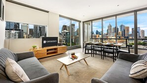 A modern living room with a city view, a flat-screen TV, a dining area, and a sofa. - Corporate Keys - Freshwater Place (Southbank)