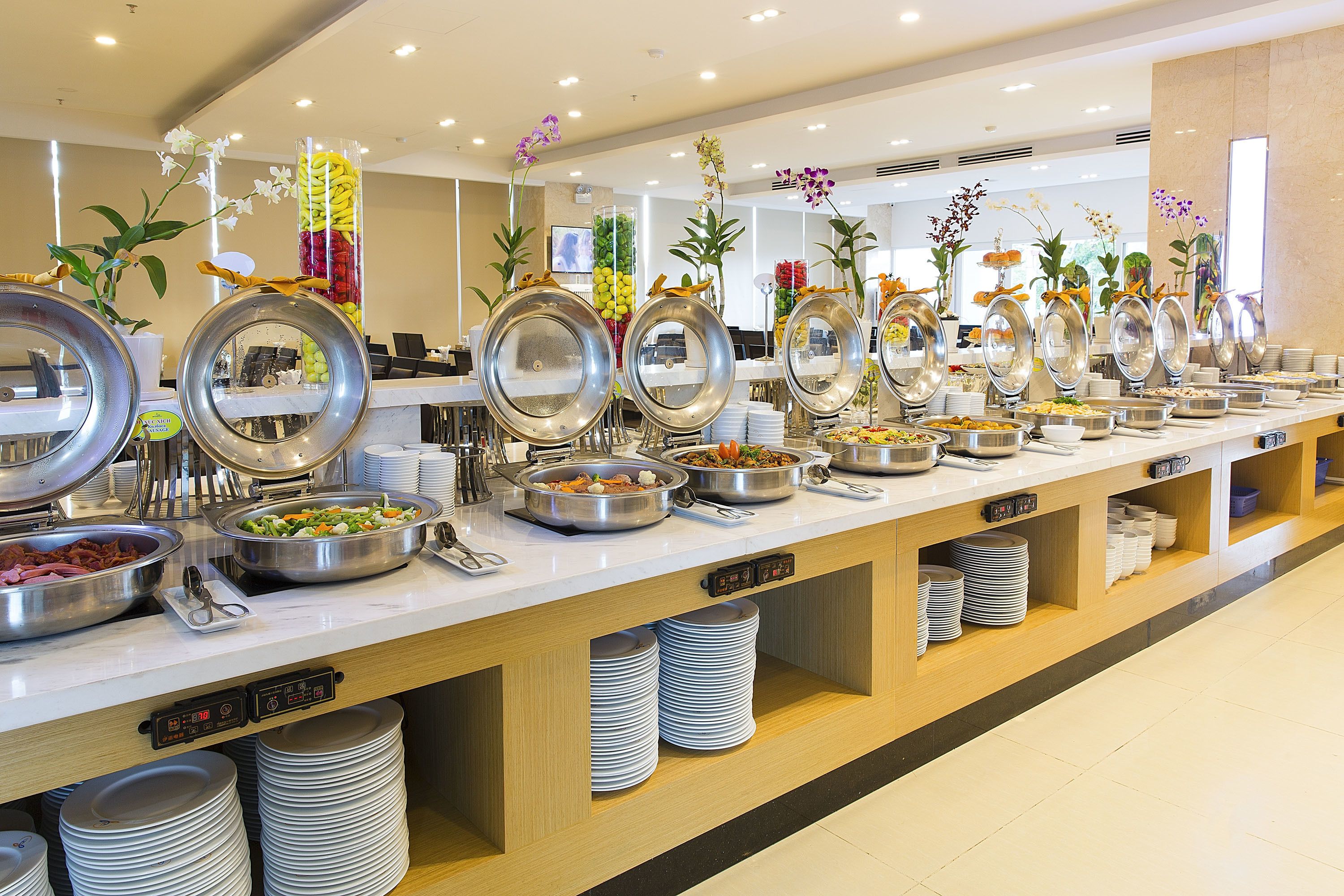 A buffet setup with various food stations, including bowls of salad, fruits, and other dishes.
