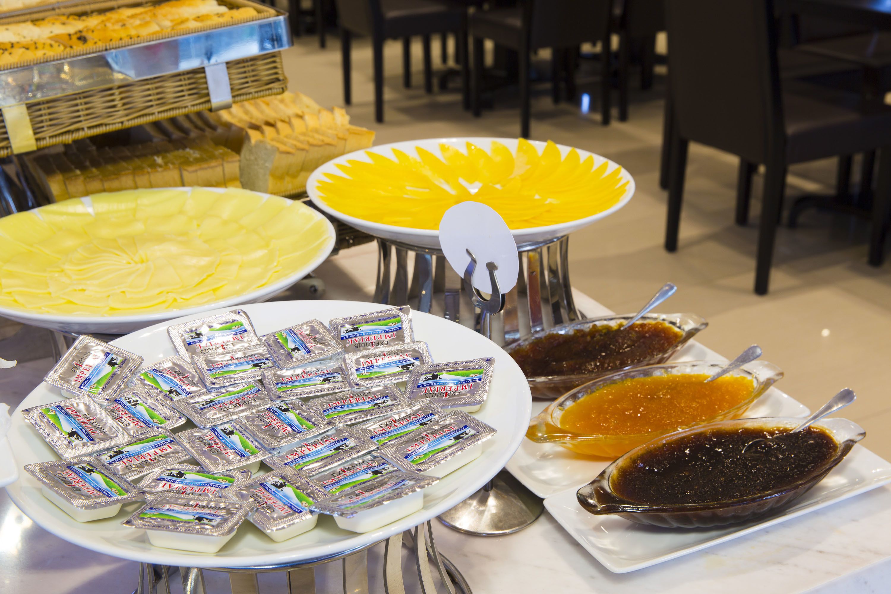 Un bufé con diversos alimentos, incluyendo un plato amarillo, una fuente con comida envasada y un plato con salsa oscura.