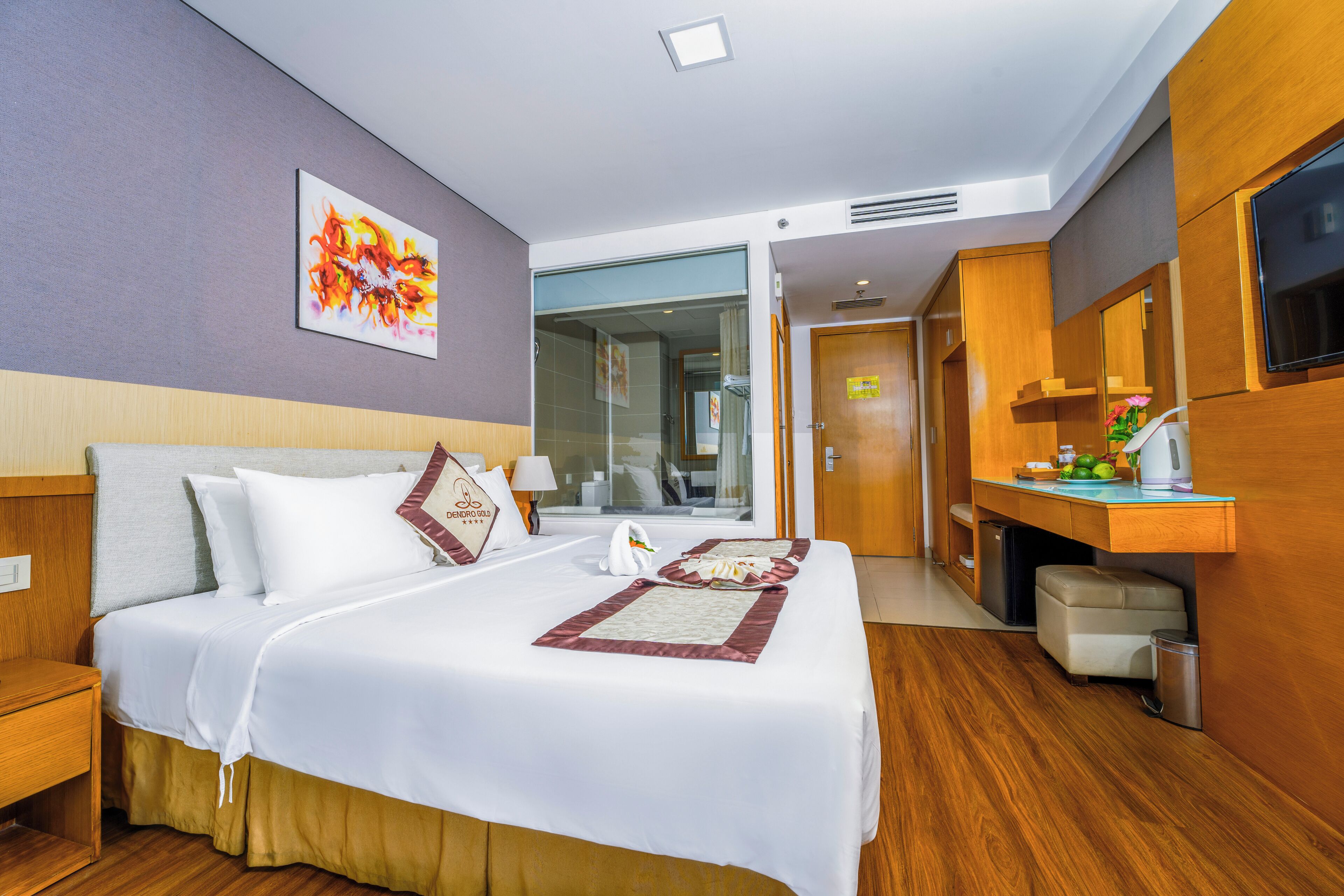 A hotel room with a large bed, a desk with a mirror, a television, and a window.