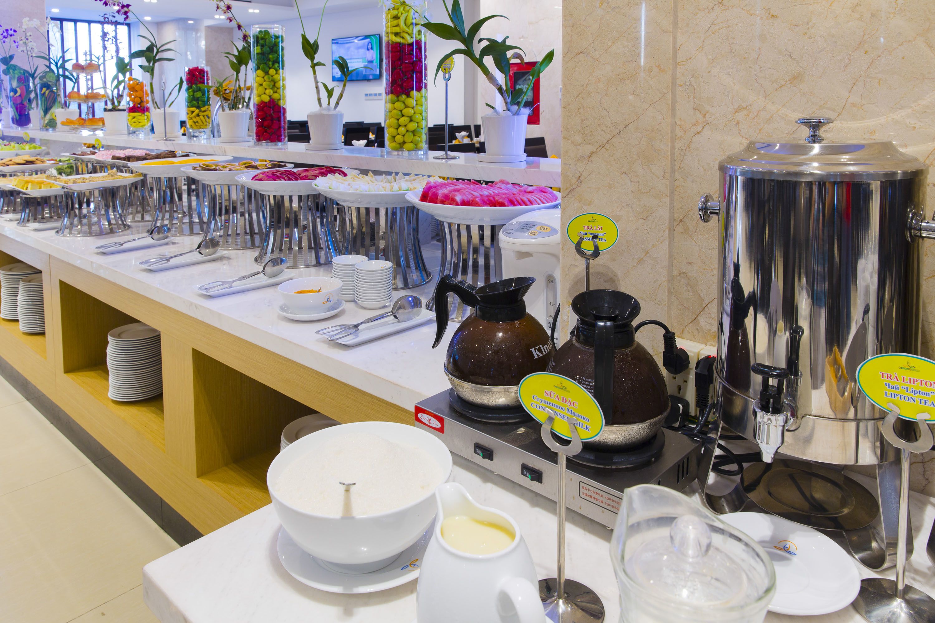 A buffet setup with various food items, serving utensils, and beverage dispensers.