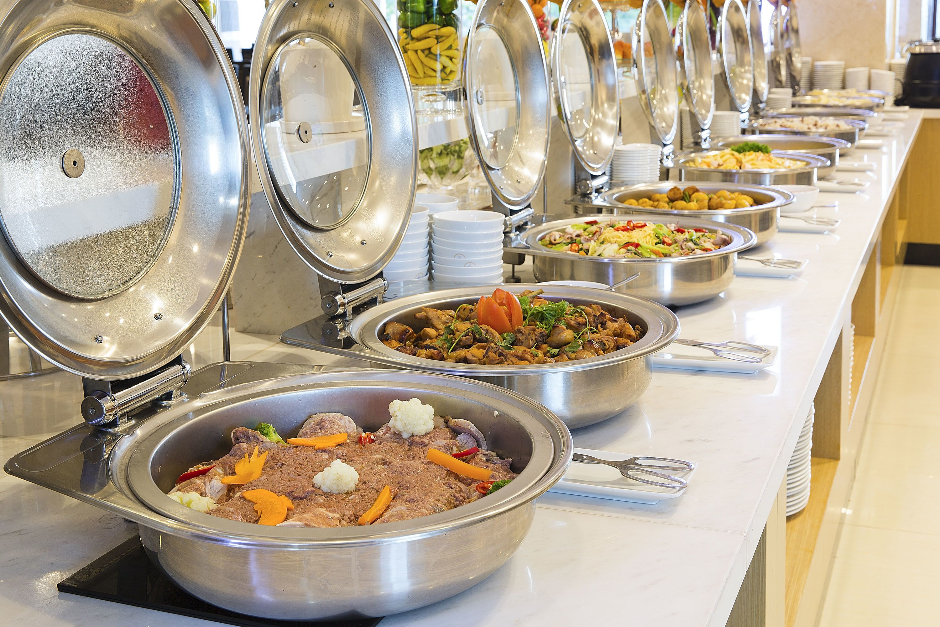 Un buffet proposant divers plats présentés dans des plats de service en métal, disposés sur une longue table.