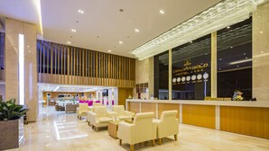 A hotel lobby with a reception desk, seating area, and a view of the city skyline. - Dendro Gold Hotel (Nha Trang)