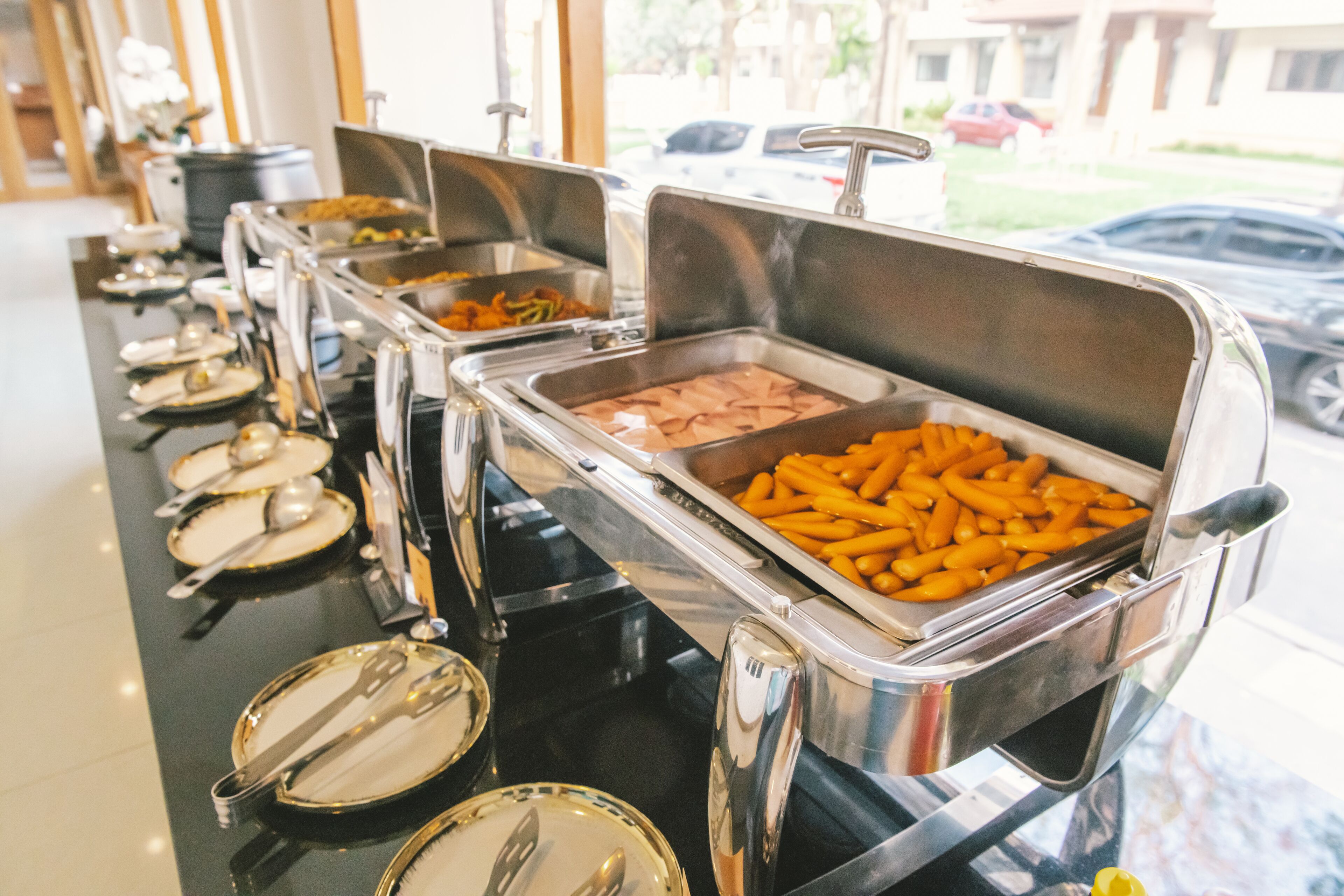 A buffet line with various food items and utensils.