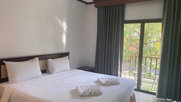 A hotel room with a large bed, two pillows, and neatly folded towels on the bed.