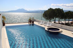 Una piscina al aire libre, sombrillas, sillones reclinables de piscina