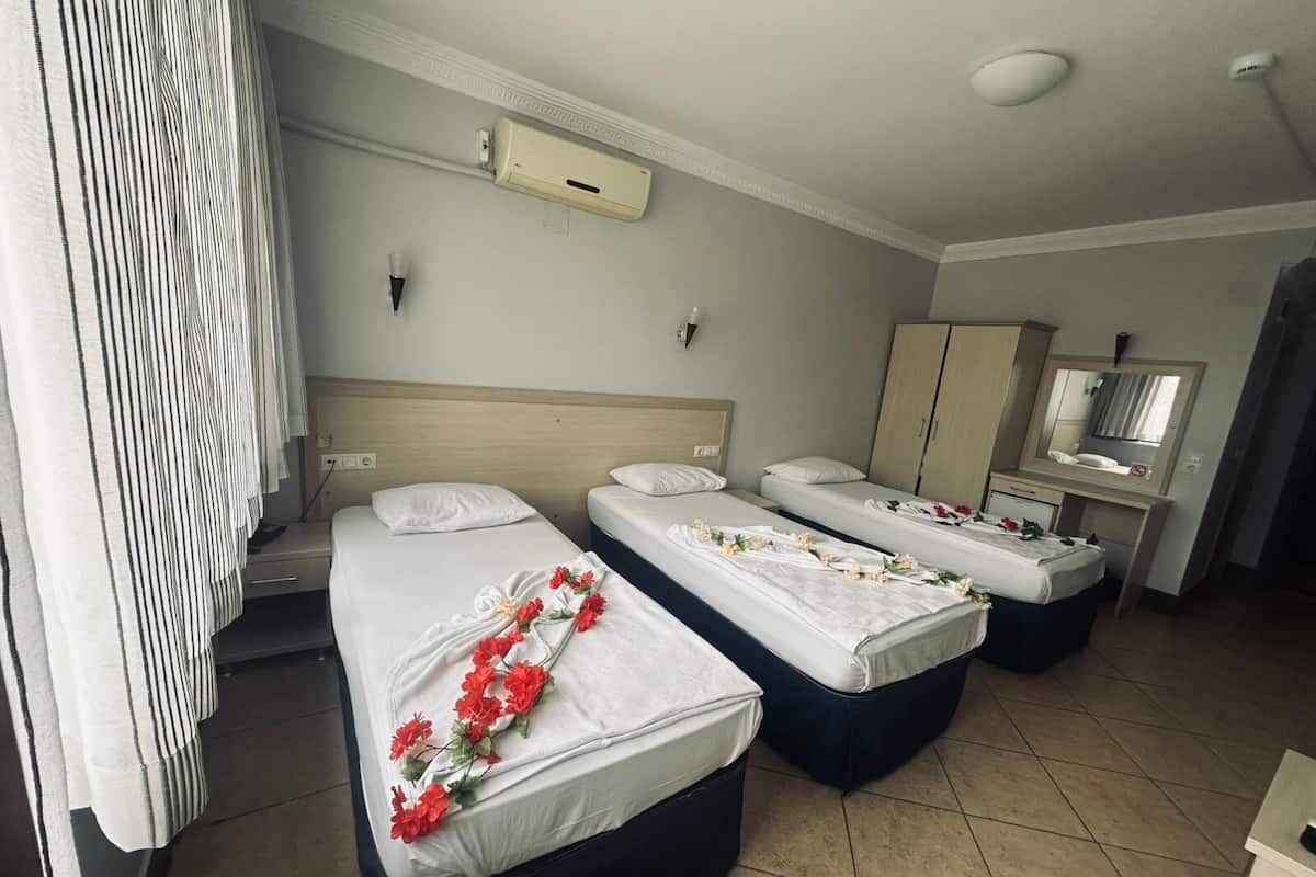 Une chambre d’hôtel avec deux lits simples, un bureau, une chaise, une armoire et un miroir.