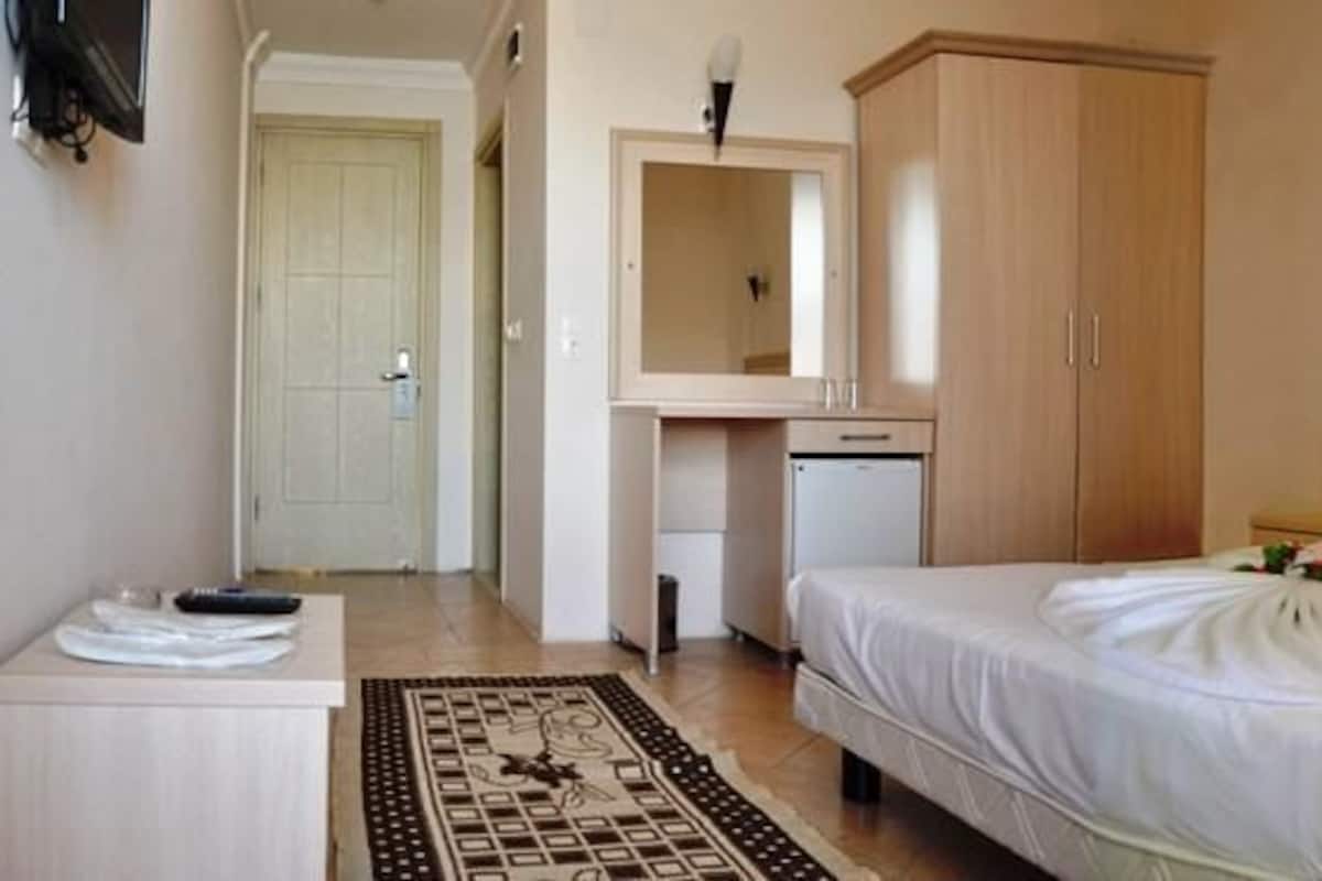 Une chambre d’hôtel comprenant un lit, une table de chevet, un bureau avec une chaise, une armoire et une salle de bain.