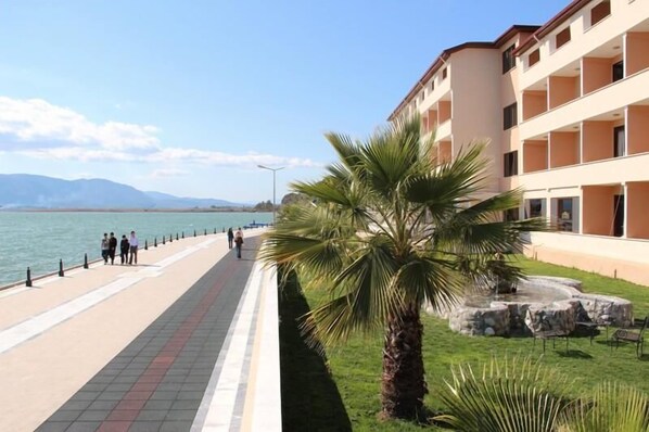 A coastal hotel with a long promenade, palm trees, and a view of the sea. - Kaunos Hotel (Koycegiz)