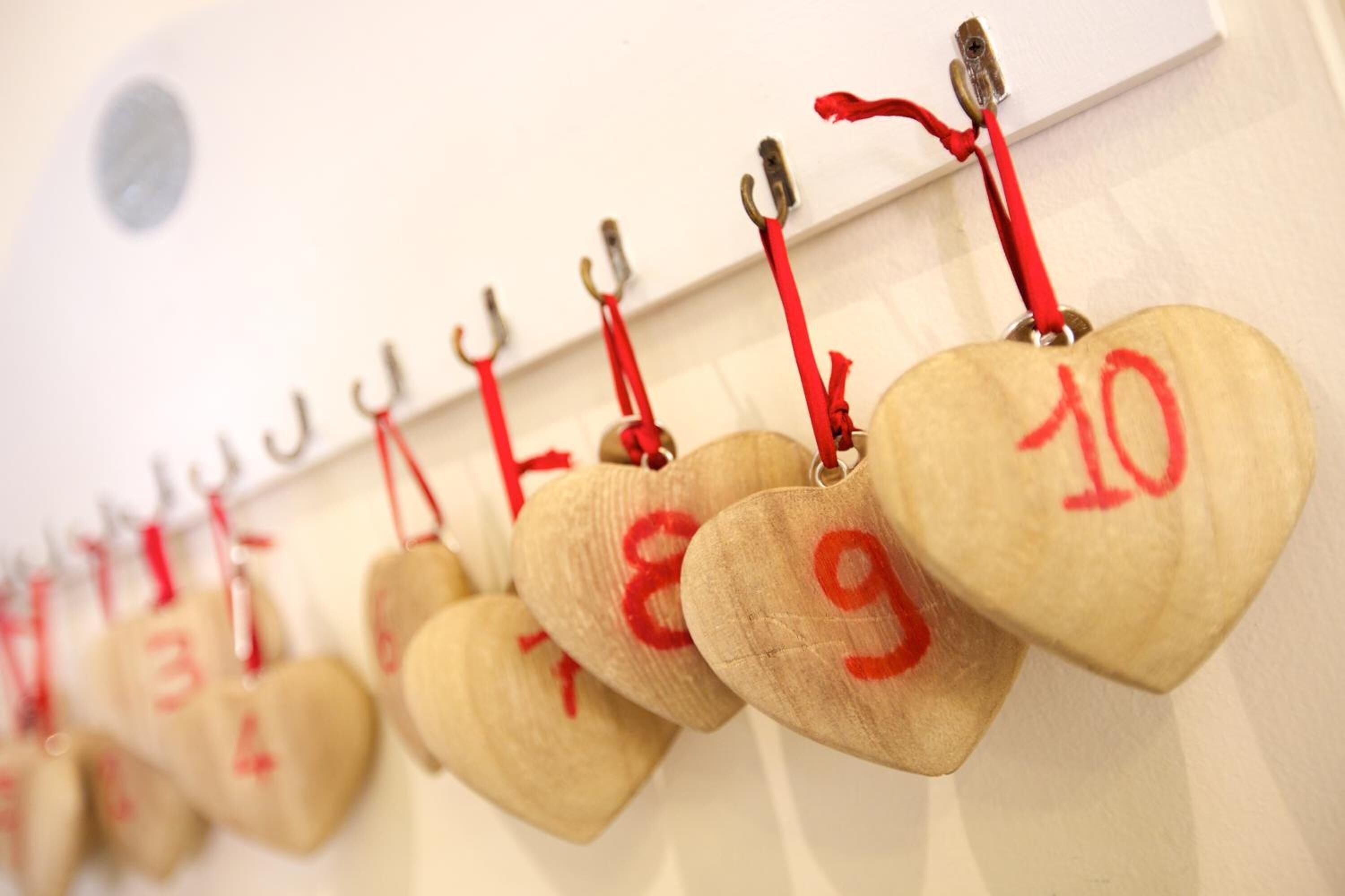 Una hilera de etiquetas de madera con forma de corazón y números, colgadas en una pared.