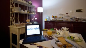 Una cocina con un ordenador portátil sobre una mesa, un frutero y varios utensilios de cocina en las estanterías.