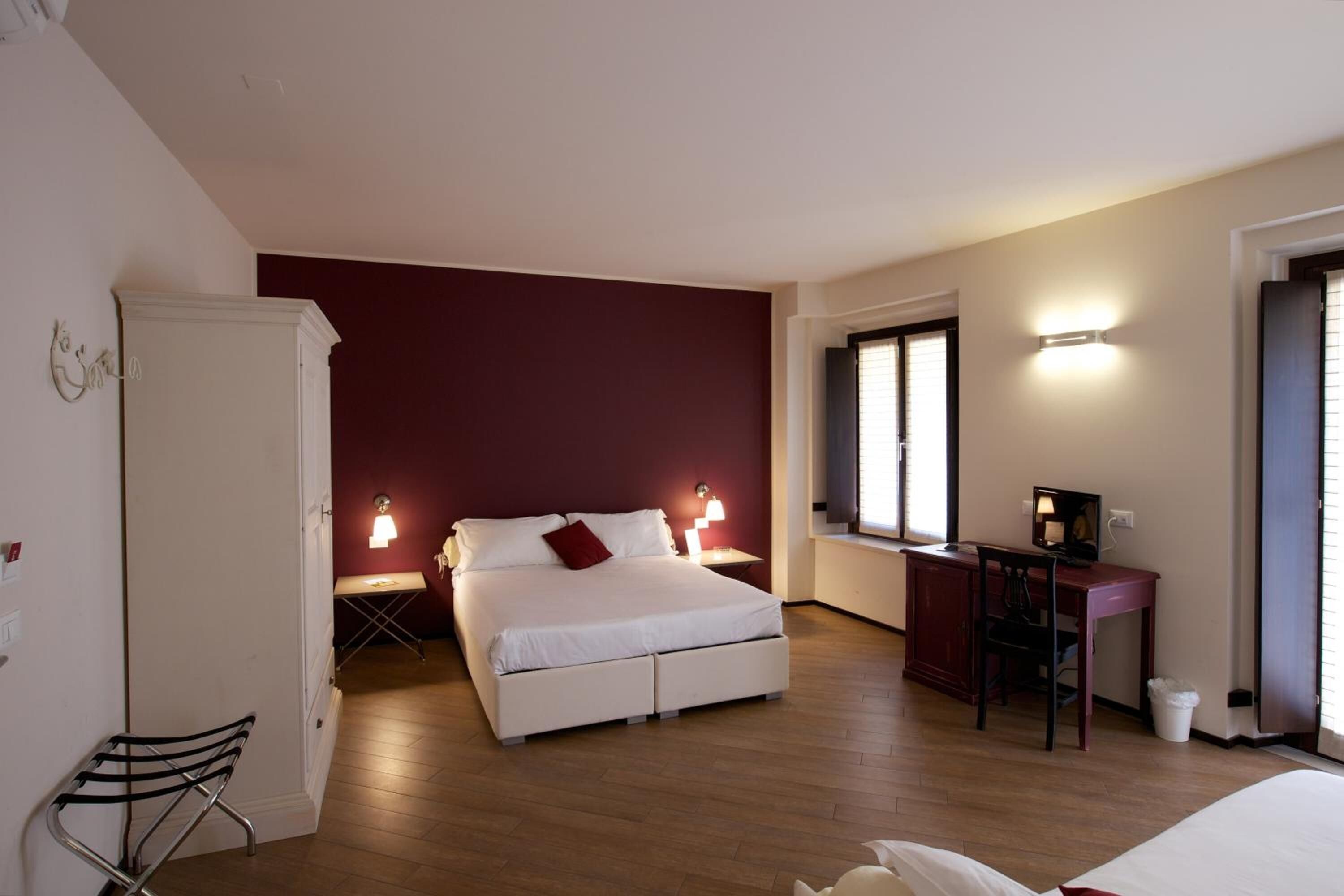 A bedroom with a bed, bedside tables, a desk, and a chair.