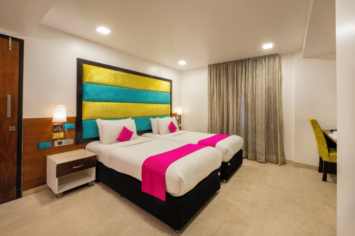 A hotel room with a large bed, bedside tables, a desk, and a chair.