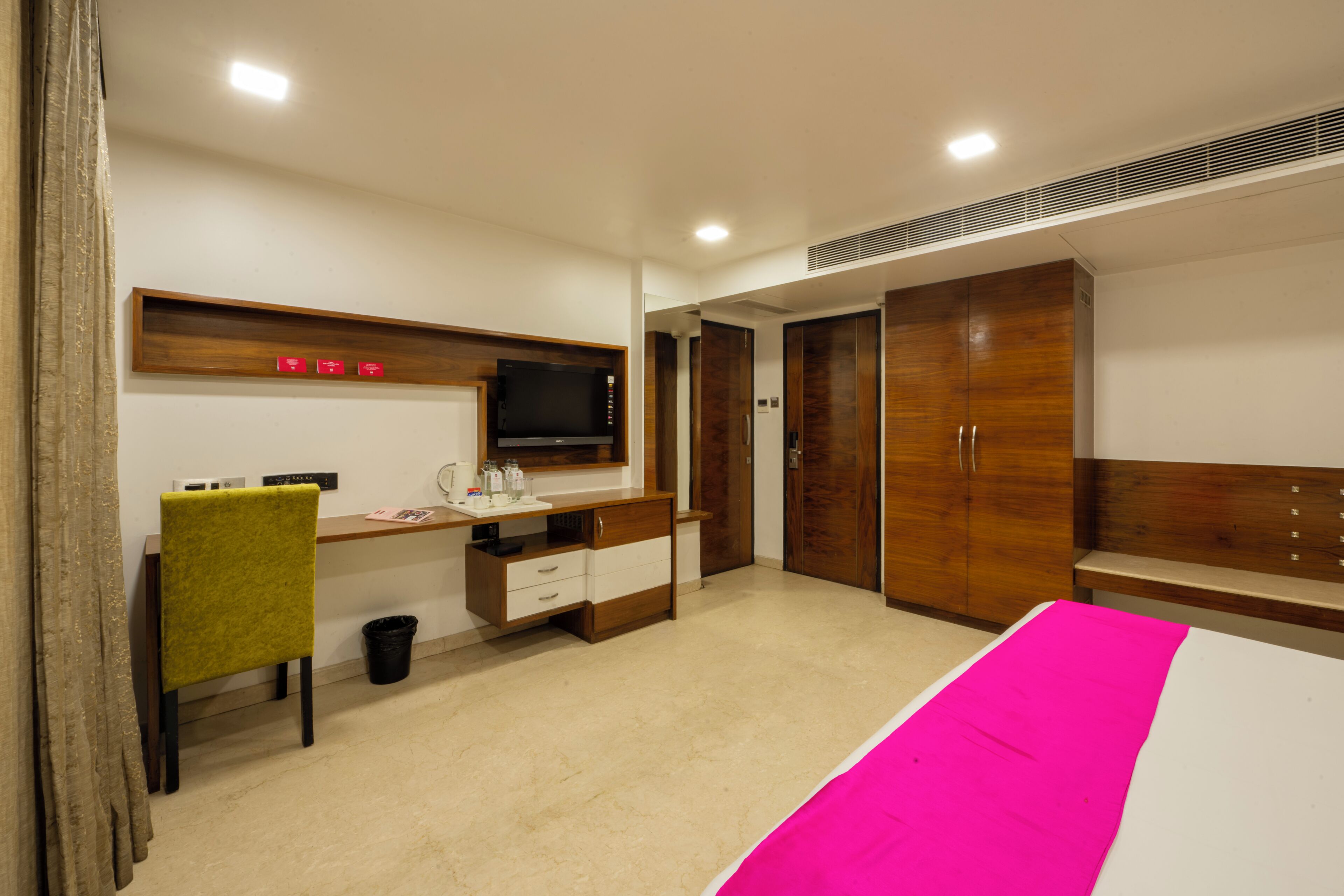 A bedroom with a bed, a desk, a chair, a TV, and a wardrobe.