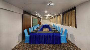 A conference room with a long table, blue chairs, and a carpeted floor.