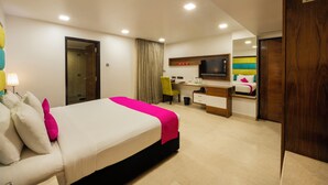 Una habitación de hotel con cama, escritorio, silla, televisor y armario.