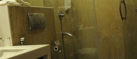 Une salle de bain moderne dotée d’une douche à parois de verre, de toilettes et d’un lavabo avec un distributeur de serviettes.