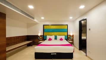 Una habitación de hotel moderna con una cama grande, un banco, una obra de arte en la pared y una puerta que da a otra habitación.