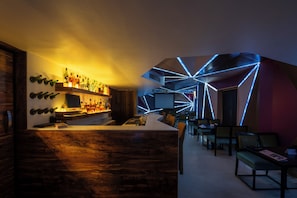 Eine Bar mit einer Holztresen, Flaschenregalen und einer Sitzecke mit Tischen und Stühlen.