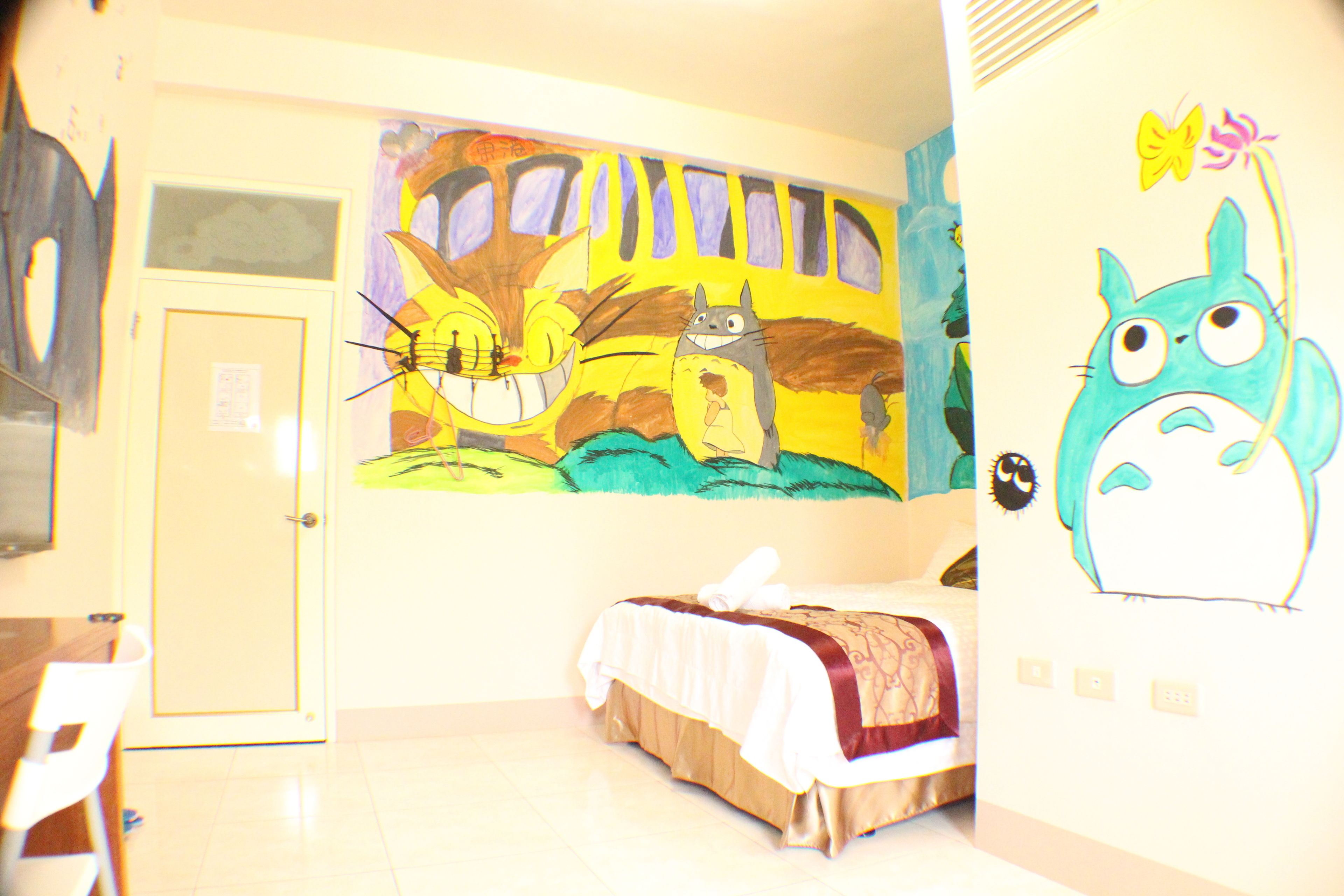Una habitación con cama, escritorio y una pared decorada con arte colorido.