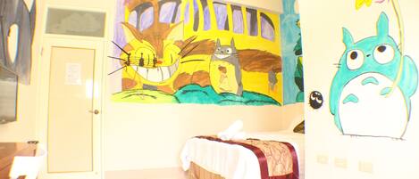 A room with a bed, a desk, and a wall with colorful artwork.