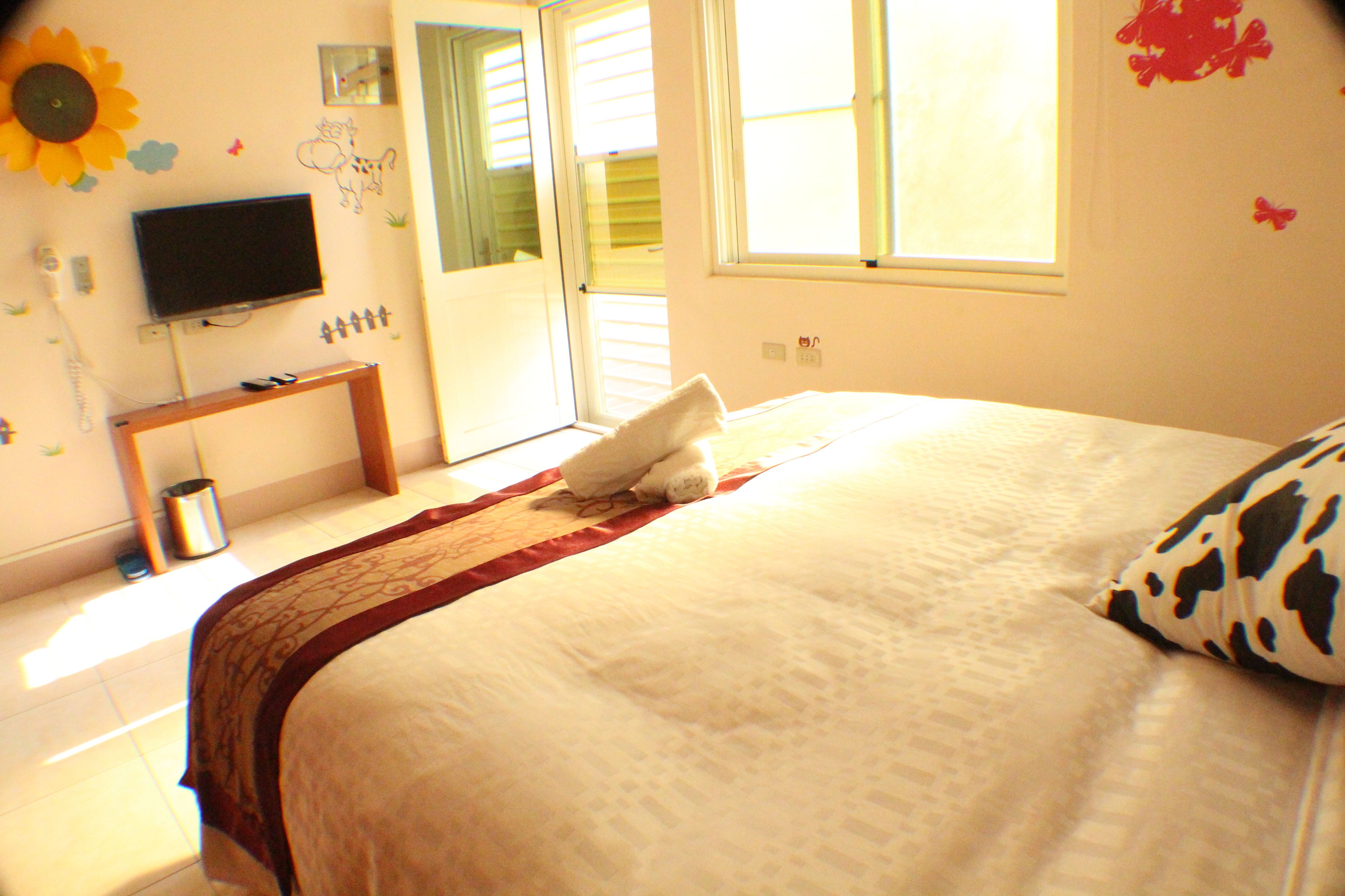 Um quarto com cama, televisão, janela e porta.