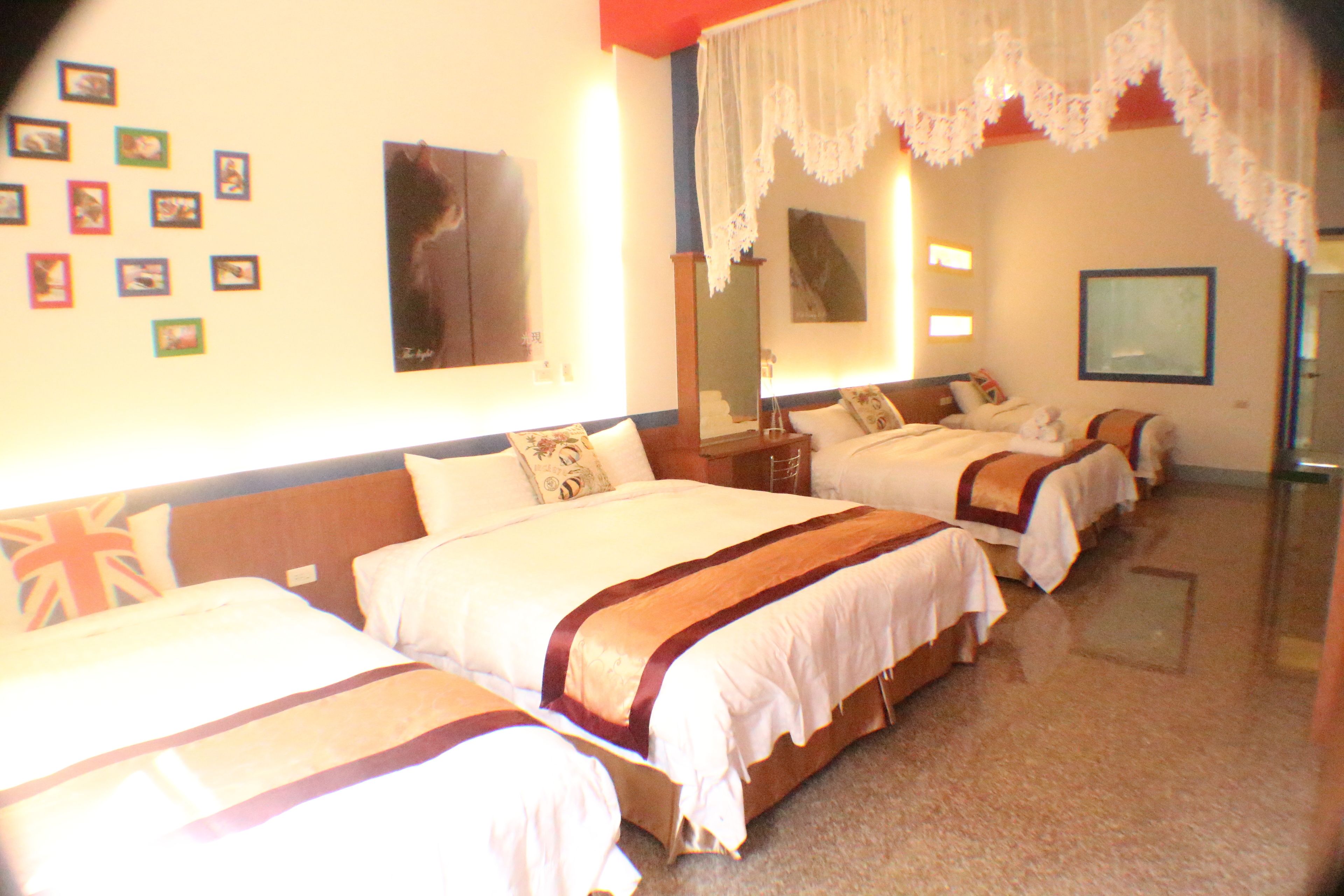 A hotel room with three beds, a large mirror, and a wall decorated with small pictures.