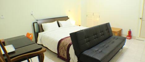 Una habitación con cama, sofá, mesa y una silla.