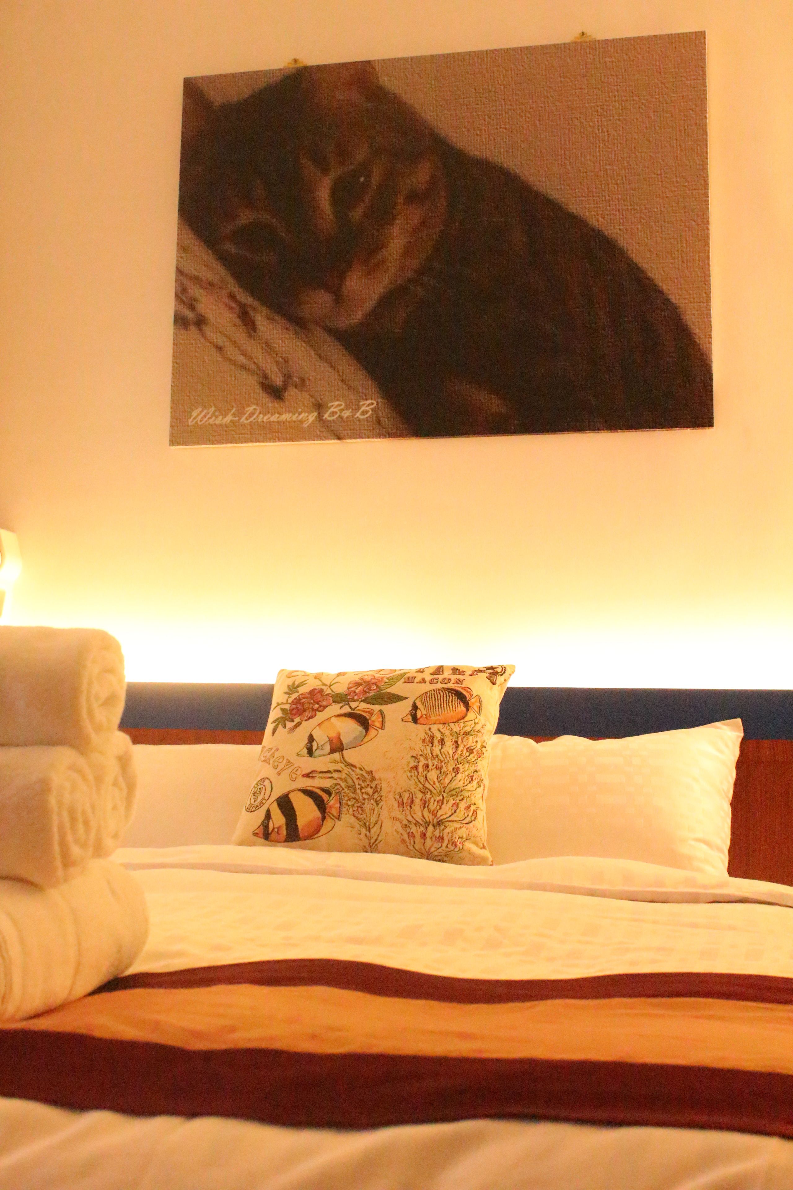 Ein ordentlich gemachtes Bett mit einer weißen Decke, einer braunen Tagesdecke und einem Kissen mit Blumenmuster.