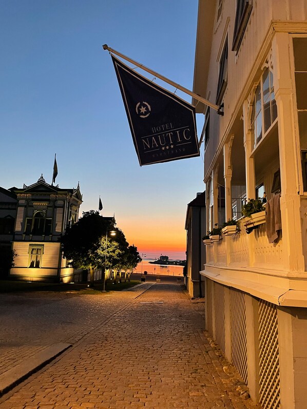 A cobblestone street leading to a building with a sign for Hotel Nautic. - Nautic Hotell (Marstrand)