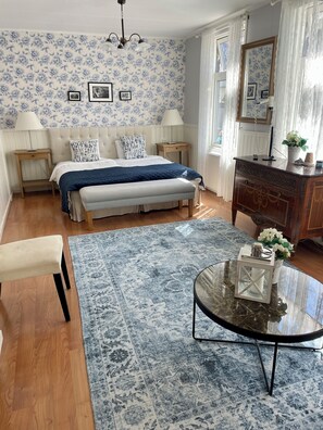 A bedroom with a bed, bedside tables, a nightstand, a bench, a glass coffee table, a dresser, and a mirror. - Nautic Hotell (Marstrand)