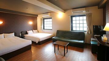 A hotel room with two beds, a sofa, a TV, and a desk.