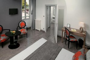Una habitación moderna con sofá, mesa de comedor, silla, radiador y televisor.