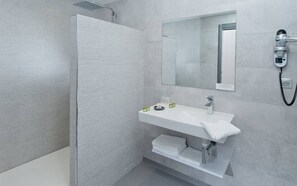 A modern bathroom with a glass shower enclosure, a white sink with a mirror above it, and a hairdryer mounted on the wall. - Hôtel Nougier (Fursac)