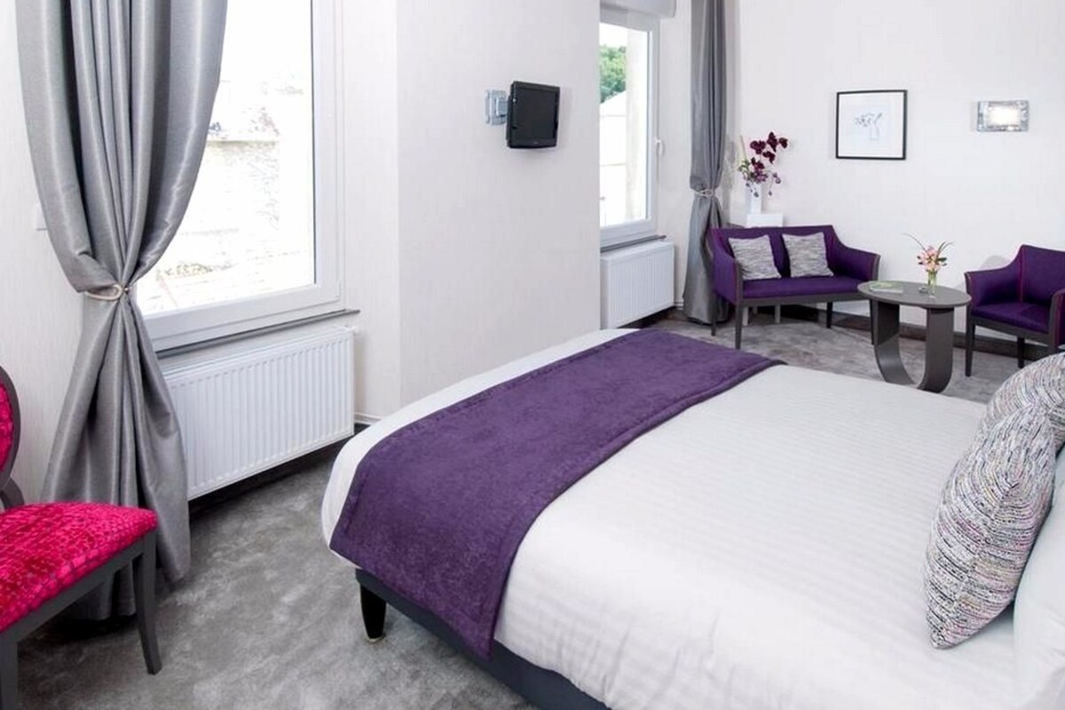 A hotel room with a bed, a chair, a small table, and a sofa.